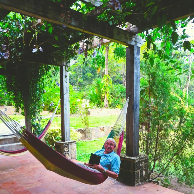 a man laying in a hammock reading a book