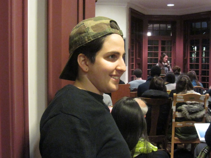 a woman in black sweater wearing a military look cap