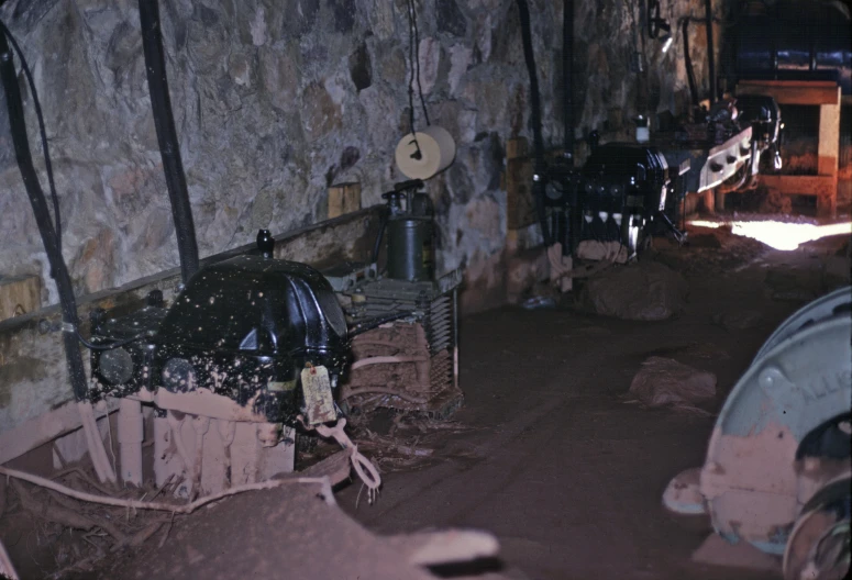 several old mechanical machinery sitting in a stone wall