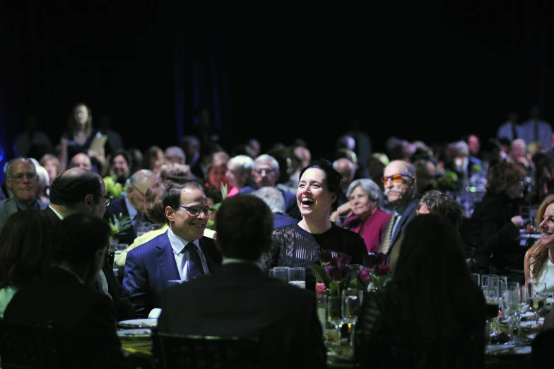 a large group of people sitting at table in front of stage