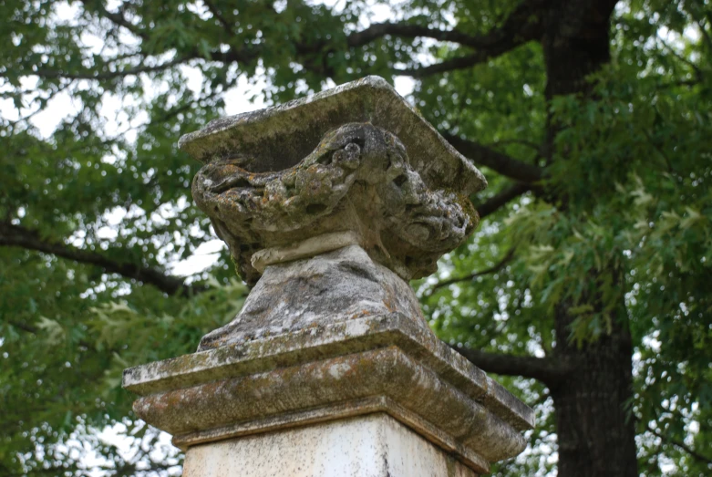 a stone pedestal sitting next to a tree