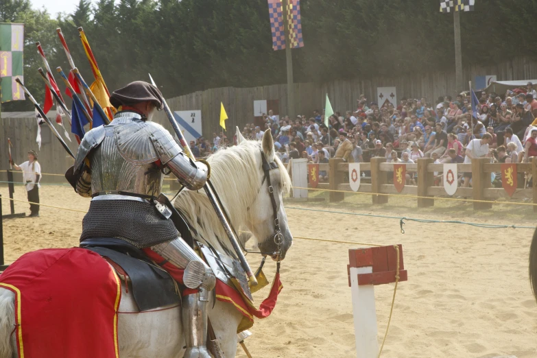 two men in armor on horses are standing with spears