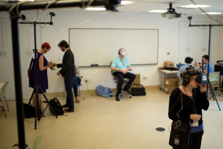 people standing around in a room while some are recording