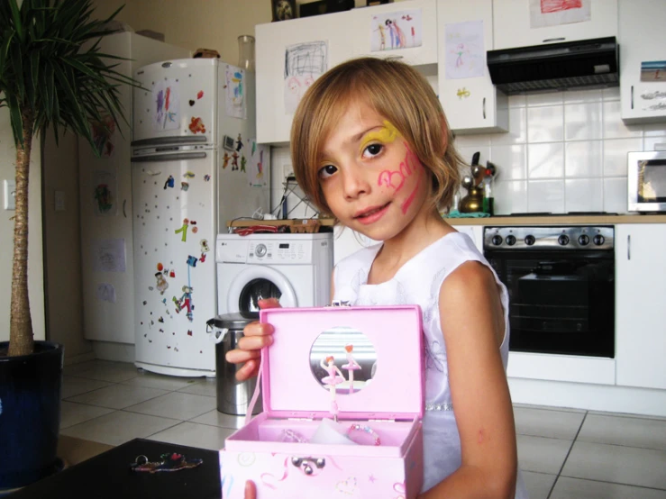 a  is holding a doll with pink stuff on her face