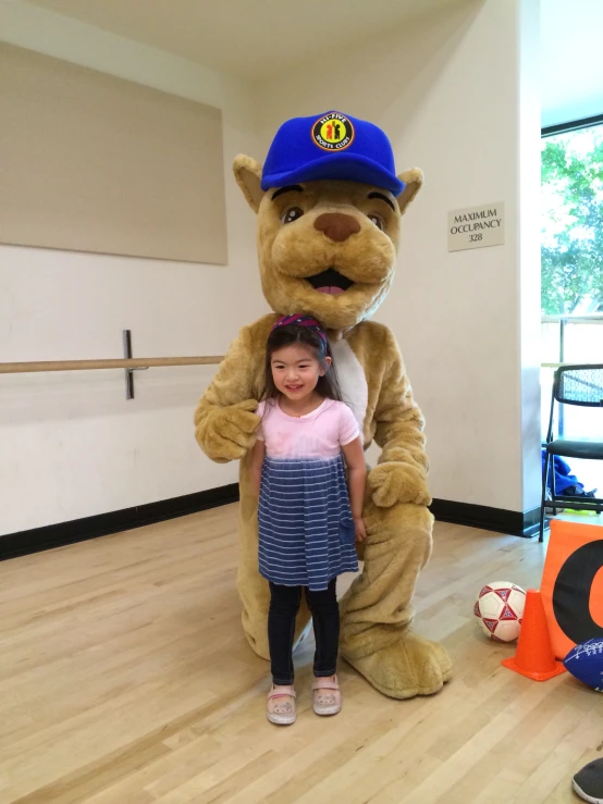 a little girl is standing with the mascot