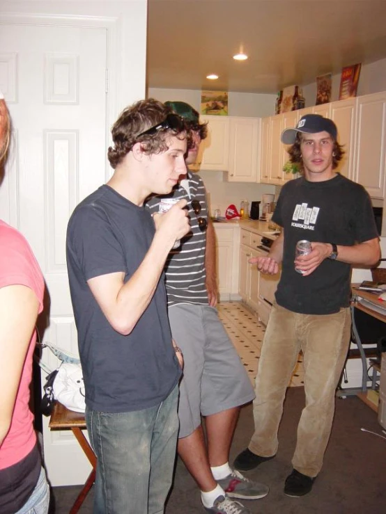 two young men are drinking in the kitchen