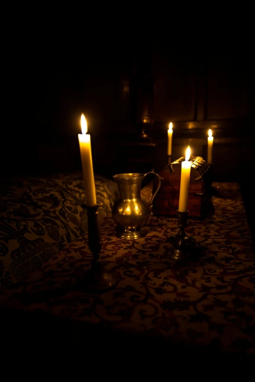 two candles in dark room with large floral tapestry