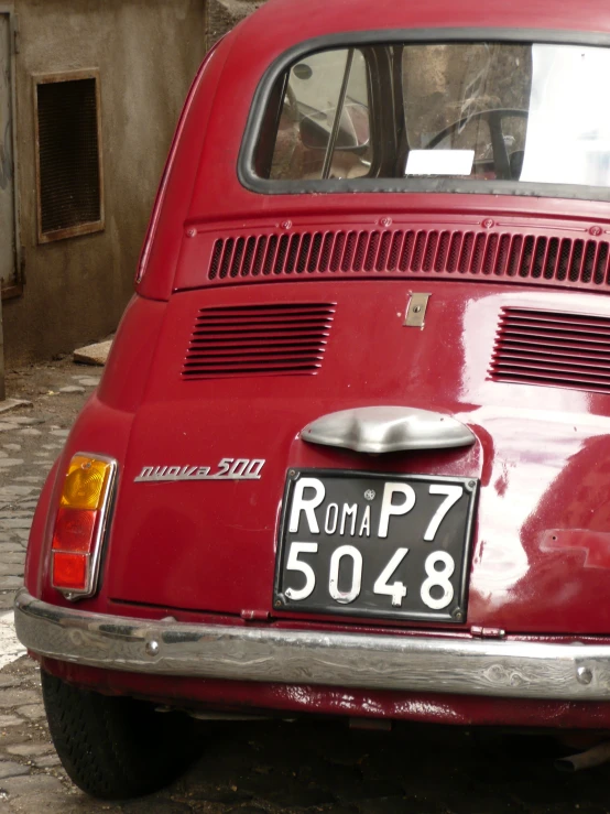 a red old car with an license plate for a motor car