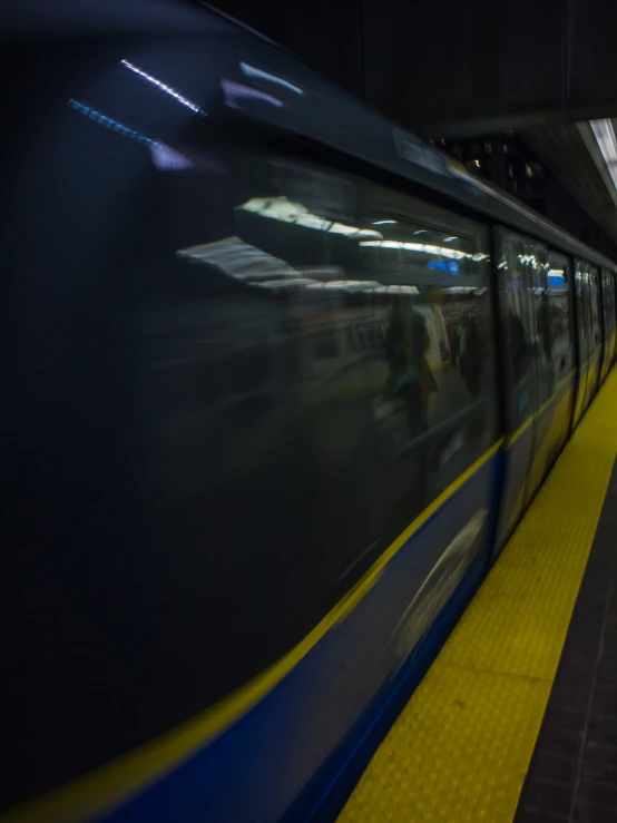 a moving train speeding by some people waiting at a station