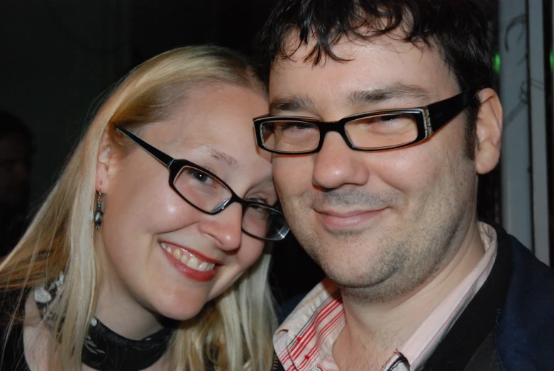 a smiling woman is next to a man with glasses