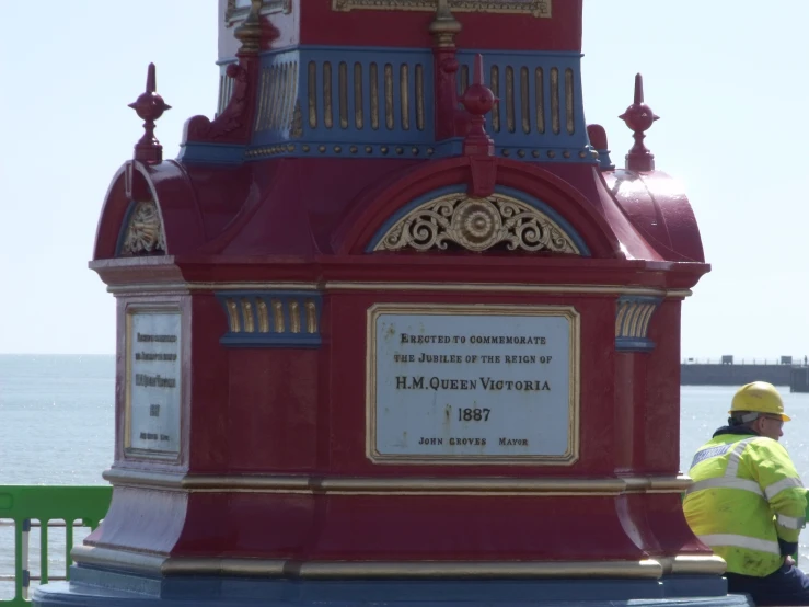 a red clock tower with a man working on it