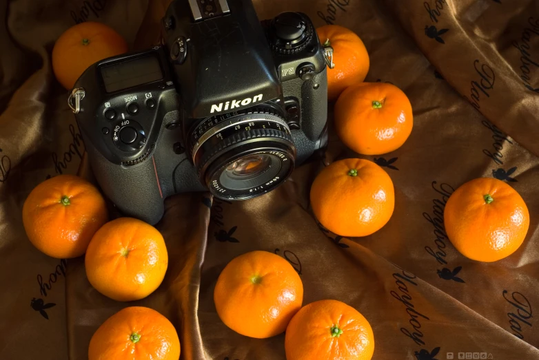 a camera and bunch of oranges are on the table
