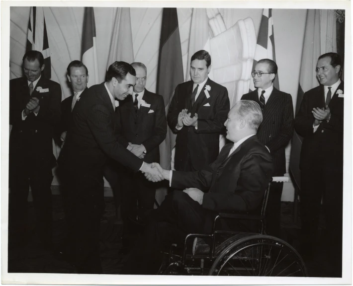 men in suits and ties shake hands in front of flags