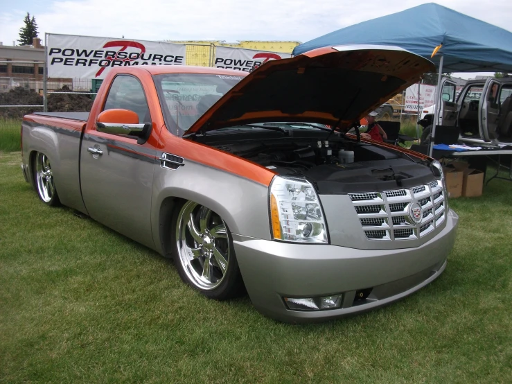 a silver truck parked on top of a field next to a tent