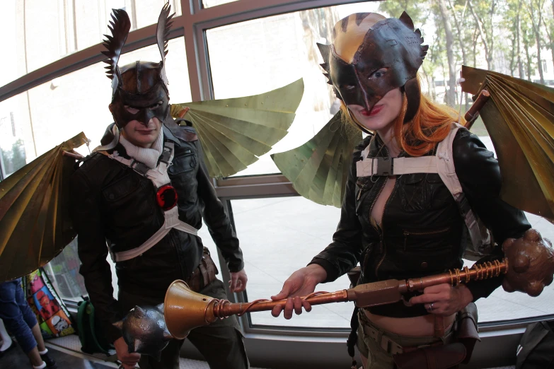 three people dressed as cats and bats are in a building