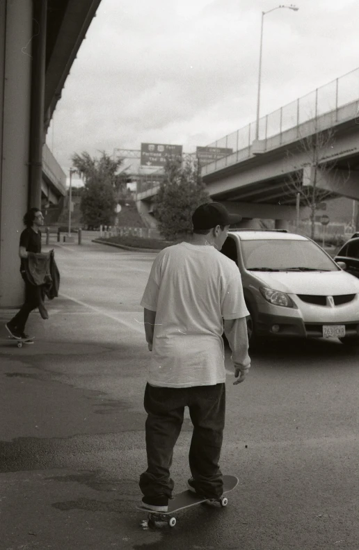 a person is skateboarding on the pavement by a car