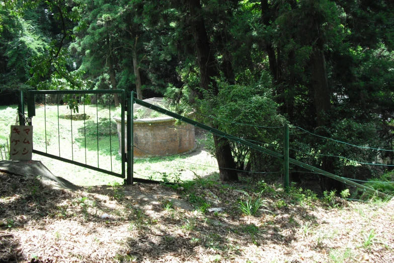 an open gated field surrounded by trees in a wooded area