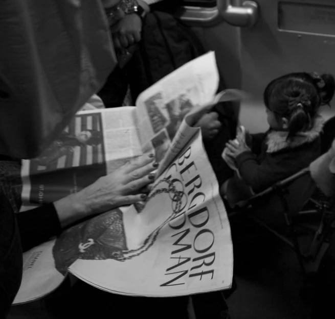 a lady holding out a magazine to a boy on a bus