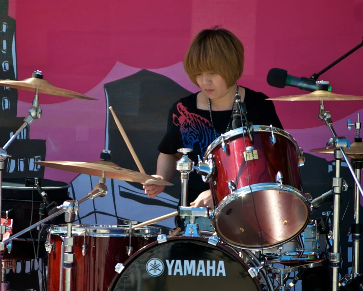 a person playing drums in front of a microphone and an advertit