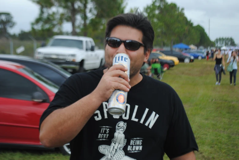 a man drinking a can while standing on the grass
