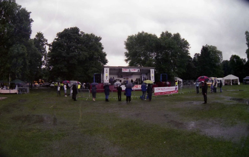 people are standing in the rain holding umbrellas