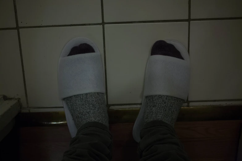 someone wearing socks standing on a tile floor