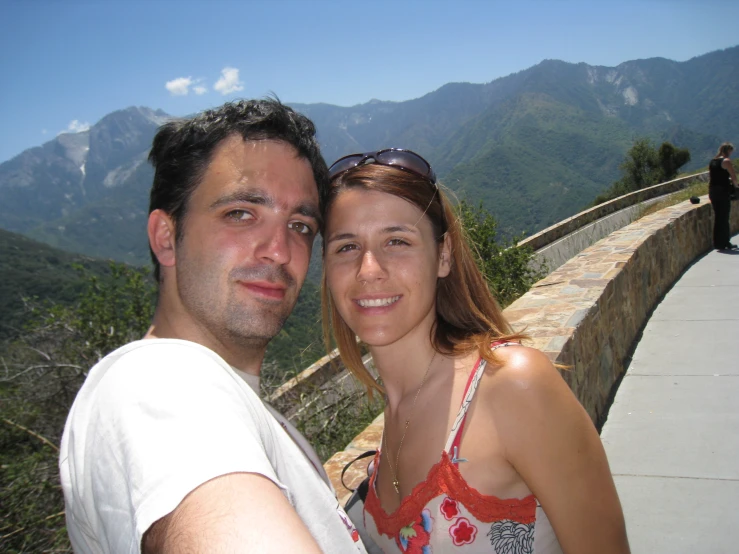 a young couple stands together on the edge of a suspension bridge