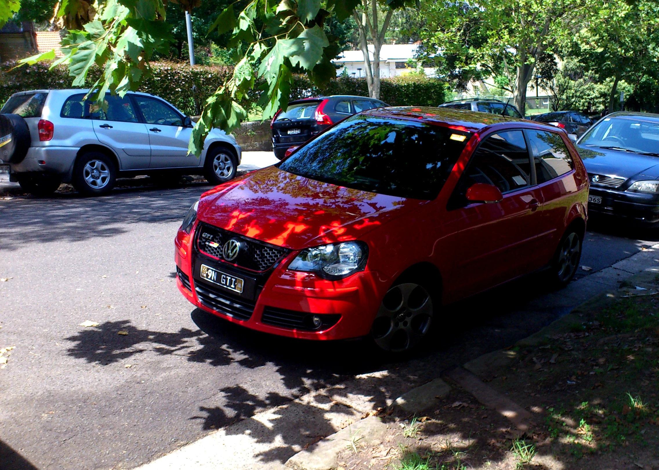 an orange vehicle parked near several cars on the side of a road