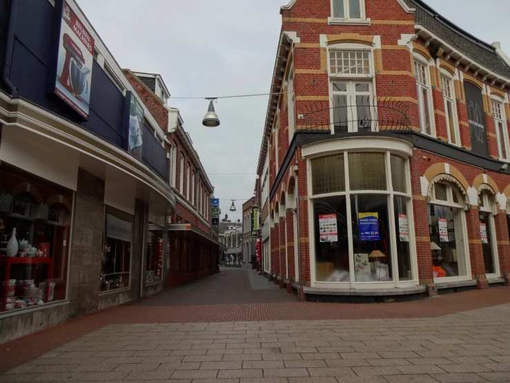 a street corner in front of a building with shops on each side