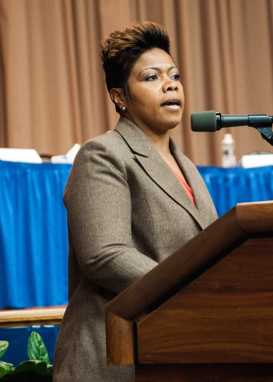 a woman in suit speaking at a podium