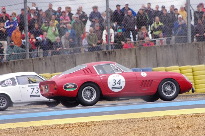 two racing cars driving in front of people