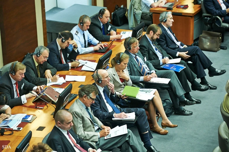 business people sit at long tables and take notes