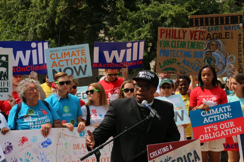 a man speaking into a microphone surrounded by political signs