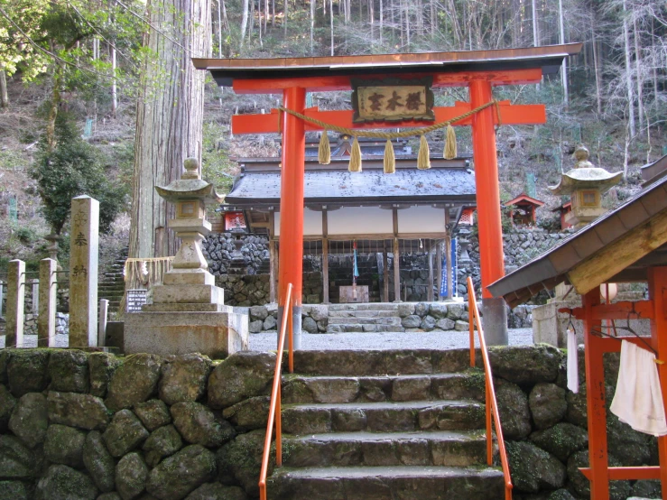 a red shrine with steps to it with the top of it in an area that appears to be surrounded by a large rock wall