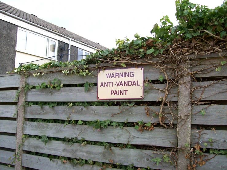 a sign is attached to a fence near some vines