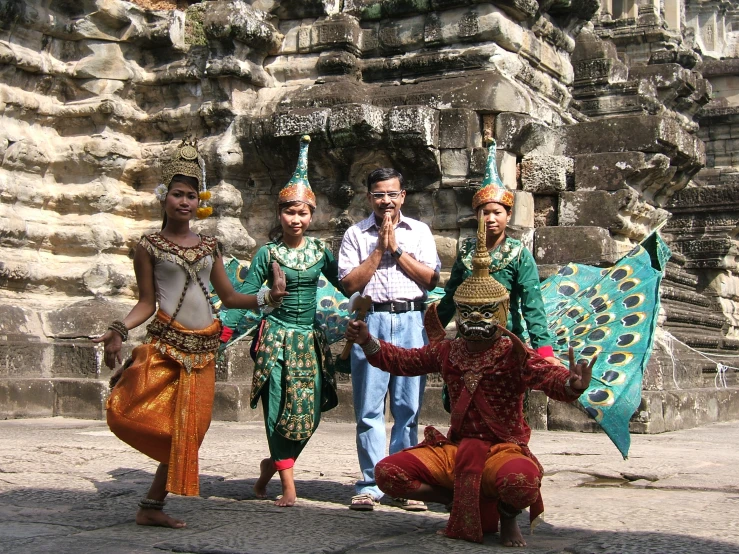 several women and men in costume stand in front of an ancient building