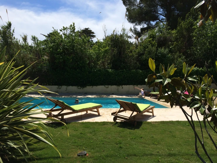 a garden with green lawn chairs next to a pool