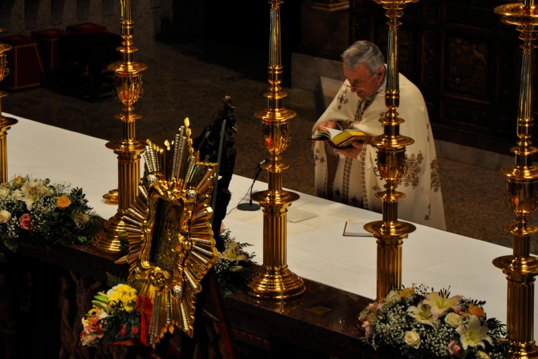 the pope looking down at a cross as she sits by him