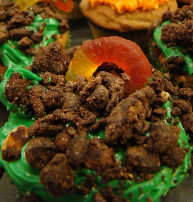 an assortment of cupcakes with green frosting and chocolate chips