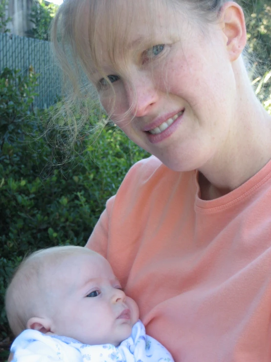 a woman smiles as she holds her baby