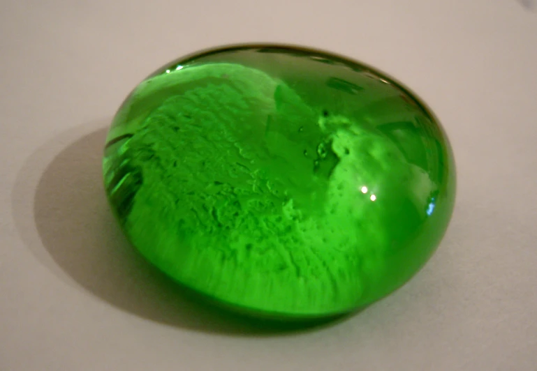 a green glass object sitting on top of a white table