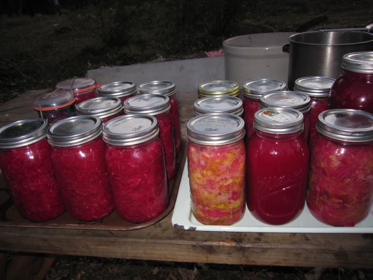 many jars with pickled vegetables on them and a wooden shelf