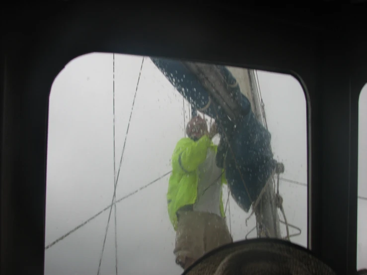 a man in a yellow jacket looking out of a window