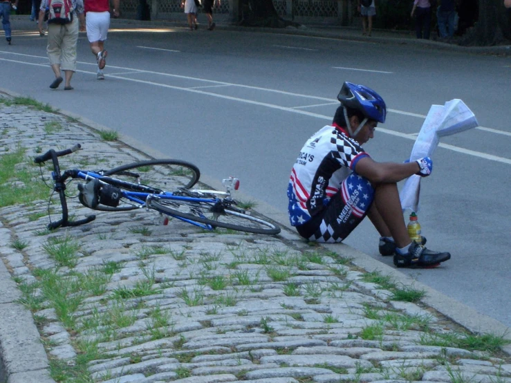 a man sits in the street with his bicycle on the ground