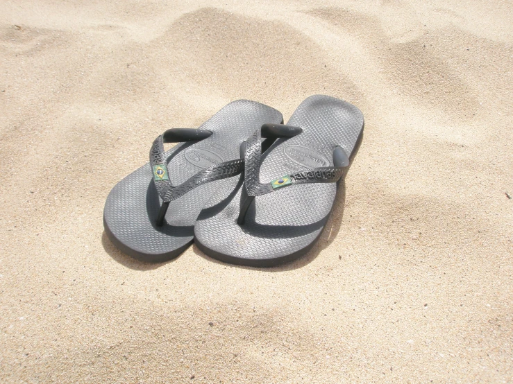 a pair of sandals laying on top of the sand