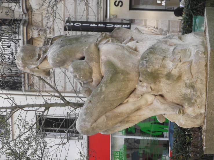 a stone statue sits on the corner of a street