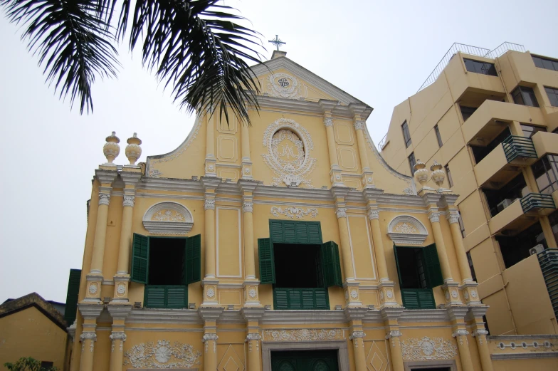 a building with shutters on each window, next to several other buildings