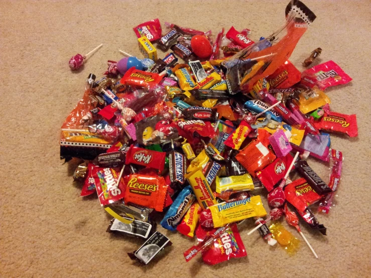 many colorful candy bars and candies are scattered over a carpet