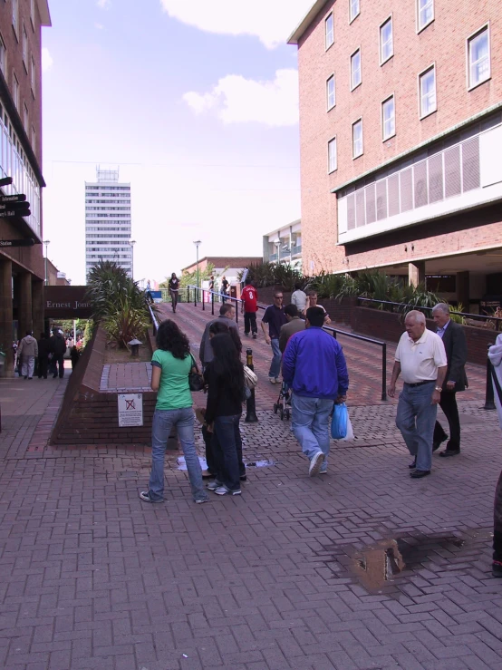 many people walking down a brick sidewalk between buildings