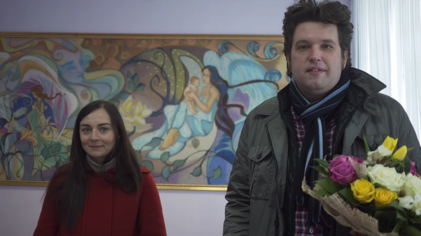 a man and woman standing in front of a painting